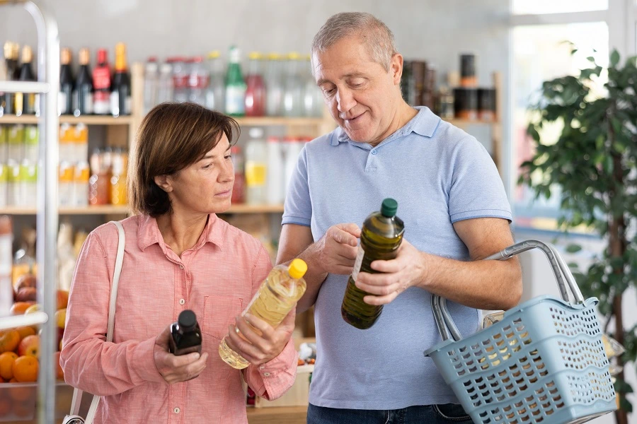 elderly man and woman looking at oil bottles in supermarket